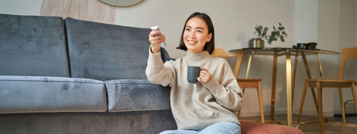 Young woman using mobile phone while sitting on sofa at home