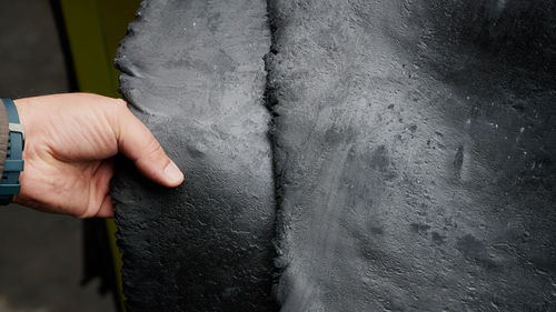 Close-up of hand holding leaf against wall