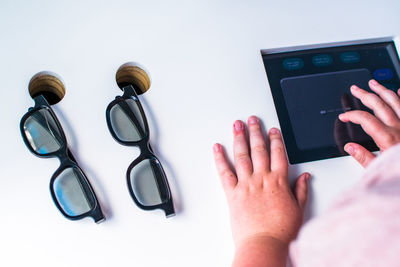Top view of eyeglasses on wooden table and hands using tablet