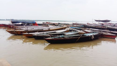 Fishing boats moored on sea against sky