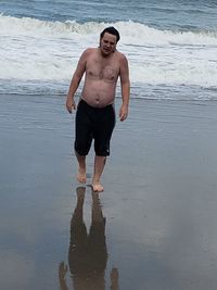 Full length of shirtless man standing on beach