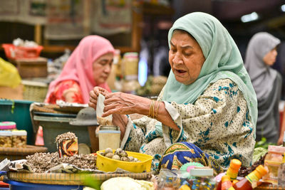 Senior woman selling food at market stall