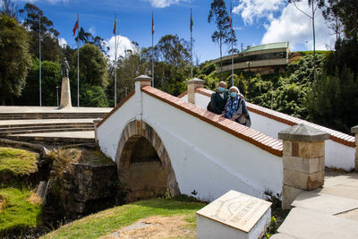 Couple wearing mask standing on bridge over canal