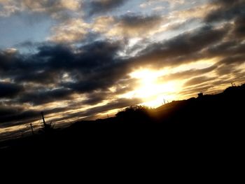 Silhouette landscape against dramatic sky during sunset