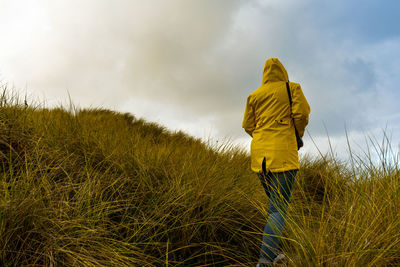 Rear view of man standing on field against sky