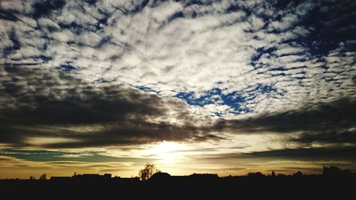 Low angle view of silhouette birds flying against dramatic sky