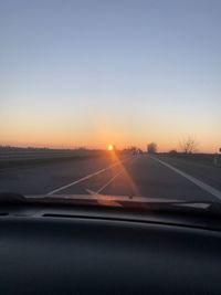 Road against sky during sunset seen through car windshield