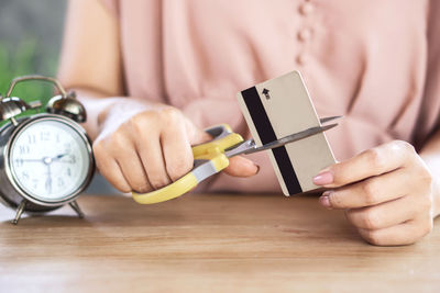 Close-up of man holding clock on table