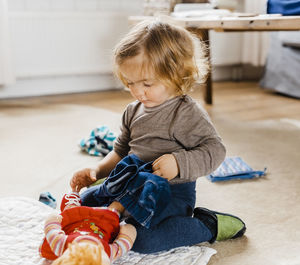 Girl playing with doll while sitting at home