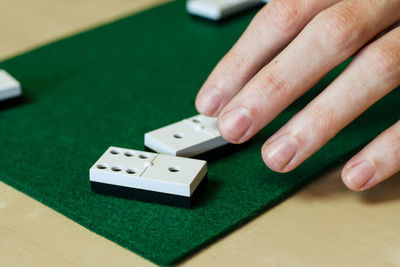 Cropped hands playing dominoes over table