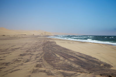 Scenic view of beach against clear blue sky