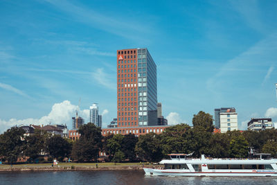 Modern buildings by river against sky in city