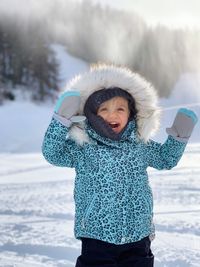 Portrait of young woman standing on snow covered field