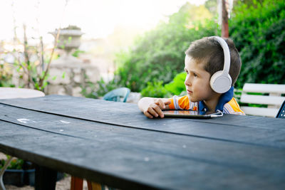 Cute boy listening music through at mobile phone outdoors