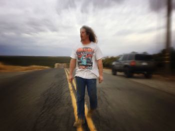 Rear view of woman walking on road in front of sea