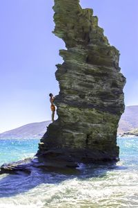 Man standing on rock formation amidst sea against sky