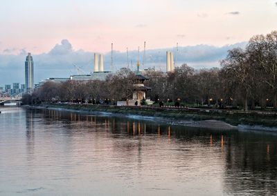 View of city at waterfront against cloudy sky