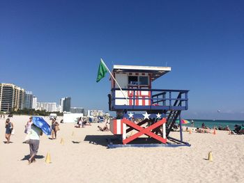 People on beach against clear blue sky