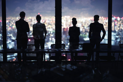 Rear view of silhouette people standing at table