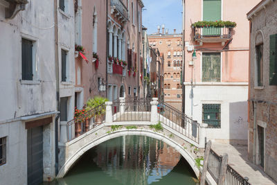Arch bridge over canal amidst buildings in city
