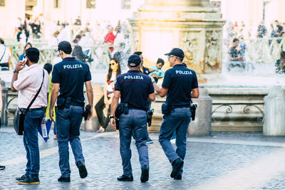 Rear view of people walking on street in city