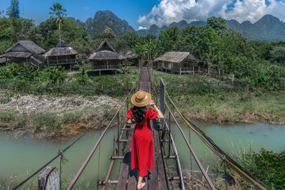 Asian female tourist walks on a wooden bridge to reach a hut in the middle of the water