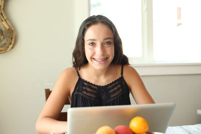 Portrait of smiling young woman using phone at home