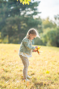 Full length of girl playing with flowers on field