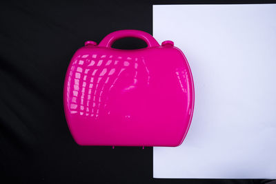 Close-up of heart shape on pink table against black background