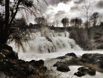 Scenic view of waterfall in forest against sky