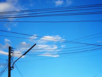 Low angle view of electricity pylon against blue sky