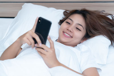 Portrait of young woman using mobile phone on bed