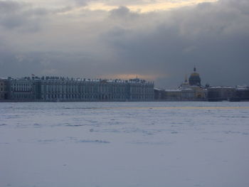 Buildings by sea against sky during winter