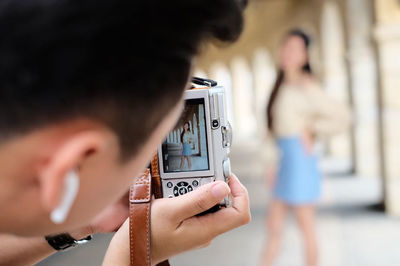 Man photographing woman from camera