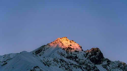 Scenic view of snowcapped mountain against clear blue sky during winter