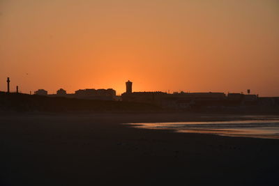 Scenic view of silhouette beach against clear sky during sunset