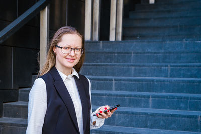 Successful businesswoman talking on mobile phone while walking outdoors near