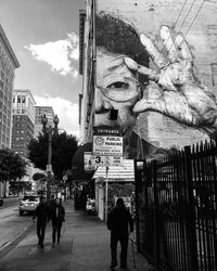 People walking on street amidst buildings in city