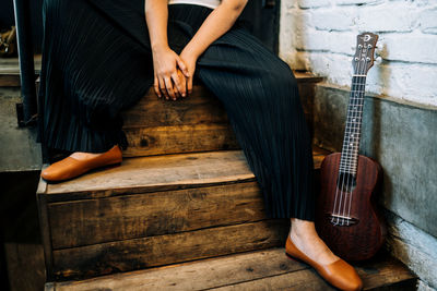 Low section of woman sitting by ukulele on steps