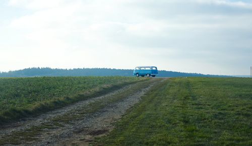 Road amidst field against sky