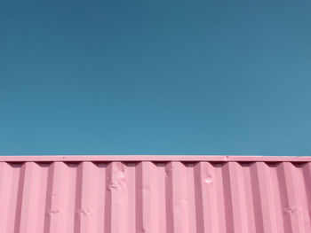 Low angle view of cargo container against clear blue sky