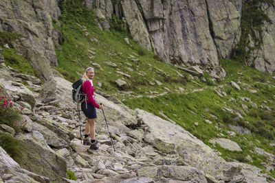 Full length side view of backpacker standing on rock