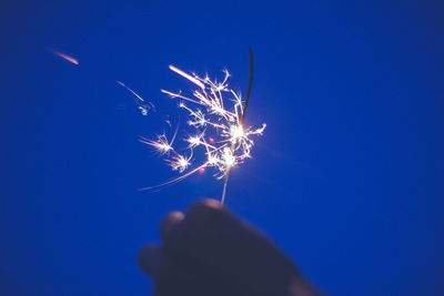 Cropped image of hand holding sparkler at night
