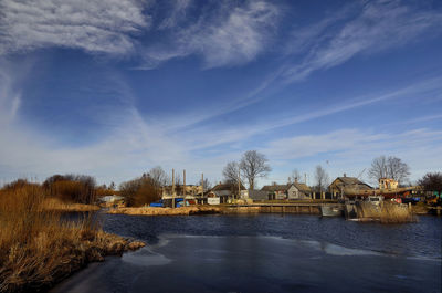 Bridge over river by buildings against sky