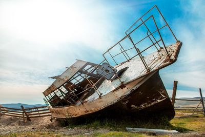 Low angle view of abandoned ship on beach against sky