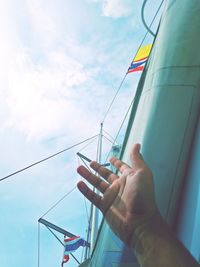 Midsection of person holding sailboat against sky
