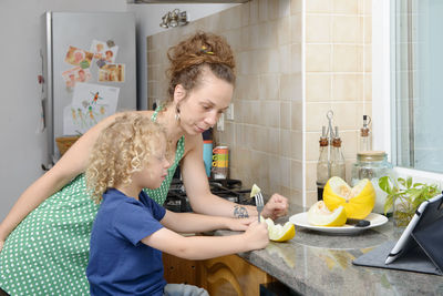 Mother looking at son having breakfast at home 