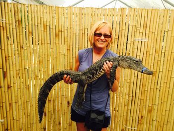 Portrait of smiling mature woman holding crocodile