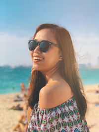 Portrait of woman wearing sunglasses at beach against sky