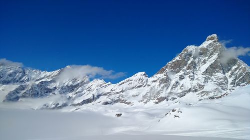 Scenic view of snowcapped mountains against blue sky